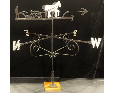 A wrought iron weather vane, the steel pointer mounted with a silhouette of a ploughman and his cart, 93cm high 