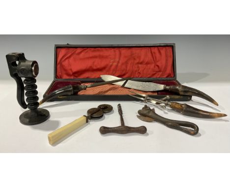 A Victorian horn handled three piece carving set; a knife sharpener; and iron corkscrew; a bull tin opener; an iron press (5)
