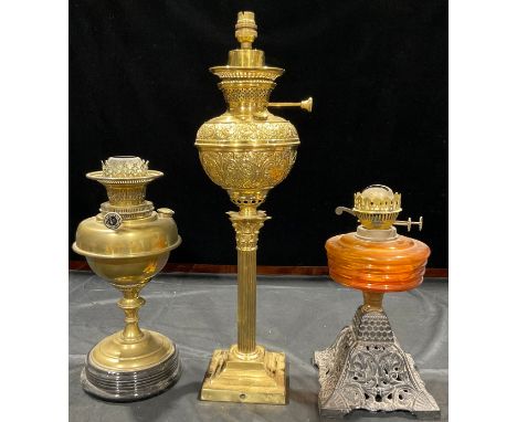 A Corinthian column brass oil lamp; a brass oil lamp; an amber glass oil lamp 
