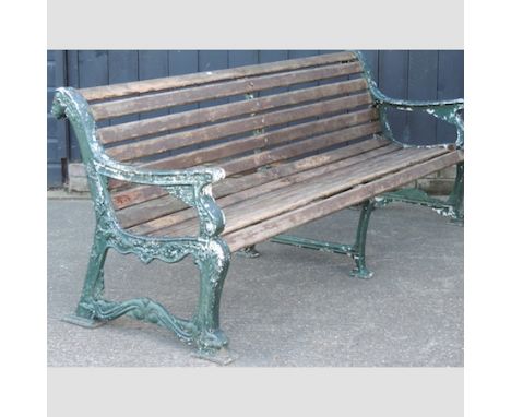 An Art Deco slatted wooden garden bench, with ornate green painted cast iron supports, terminating in lions head finials, 202