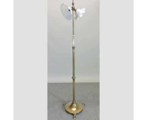 An Arts and Crafts brass telescopic standard lamp, with an opaque glass shade, on three feet