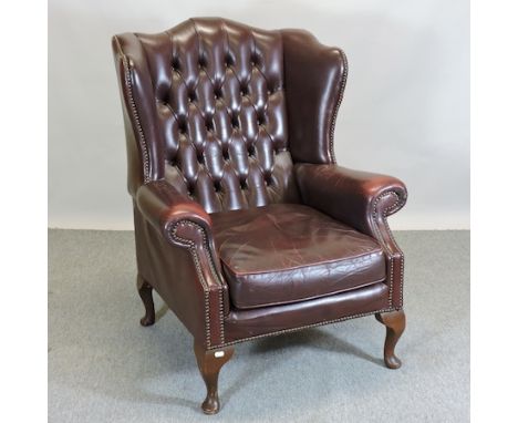 A 1920's red leather button back wing armchair