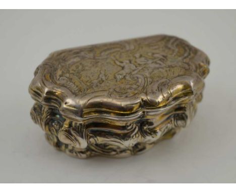 AN 18TH CENTURY PARCEL GILT WHITE METAL CONTINENTAL SNUFF BOX, of Rococo serpentine form, repousse decorated with stylised hu