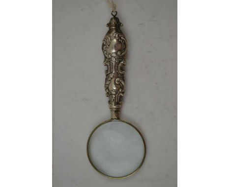 A SILVER HANDLED MAGNIFYING GLASS, the decoratively embossed handle hallmarked Birmingham 1899, the lens 4cm in diameter, ove