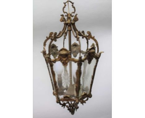 A CAST BRASS HALL LANTERN, cast Art Nouveau mask decoration, of hexagonal form, fitted clear star cut glass panels, 46cm high