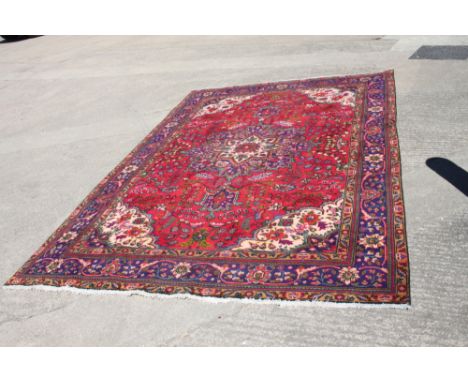 A vintage Persian Tabriz rug with central floral medallion design on a red ground with multi-borders, 117" x 77" approx 