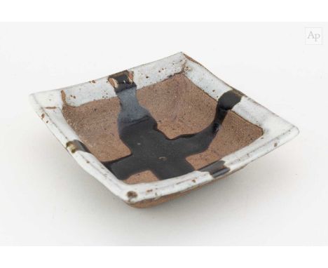 † JANET LEACH (1918-1997) for Leach Pottery; a small square stoneware dish partially covered in pale grey glaze with tenmoku 