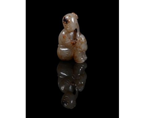 A Chinese celadon and brown jade carving of a boy and lion cub, Ming-Qing Dynasty, seated and holding a lingzhi fungus, appro
