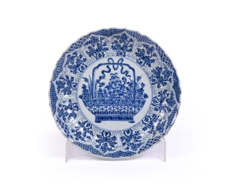 A large Chinese blue and white lobed dish, Kangxi period, decorated with an auspicious flower basket within scroll lappet bor
