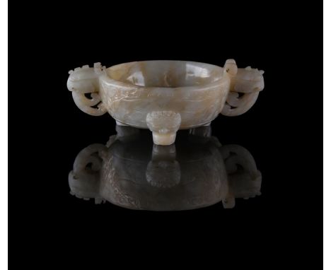 A Chinese pale celadon jade twin handled tripod censer, 17th century, carved in relief with taotie masks to the sides, 10cm d