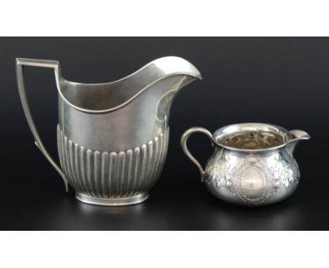 Two Victorian silver cream jugs, the first with half-gadrooned body, the other with embossed floral decoration, both London, 