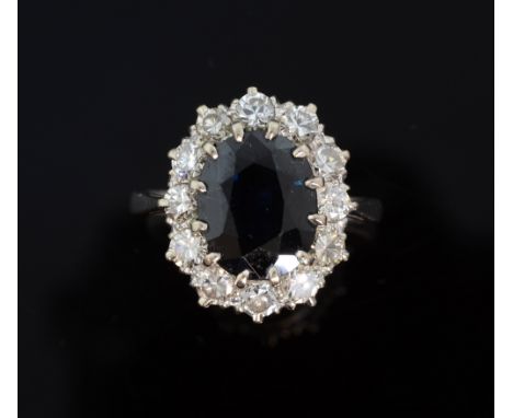 Sapphire and diamond cluster ring. Oval-cut sapphire to centre weighing approximately 4.40cts with a surround of twelve round