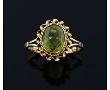 Peridot and gold dress ring.  oval-cut peridot to centre within a gold twisted border mounted in 9ct yellow gold.