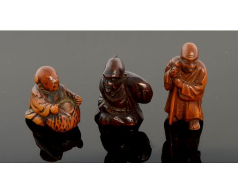 Three Japanese carved boxwood Netsuke designed as two sages and a young child playing with a Lotus Blossom