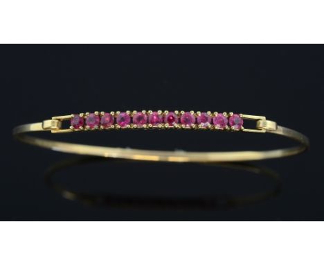 Ruby and gold bangle. Set with eleven round-cut rubies in a claw setting. mounted in 9ct yellow gold, Circa 1980's 