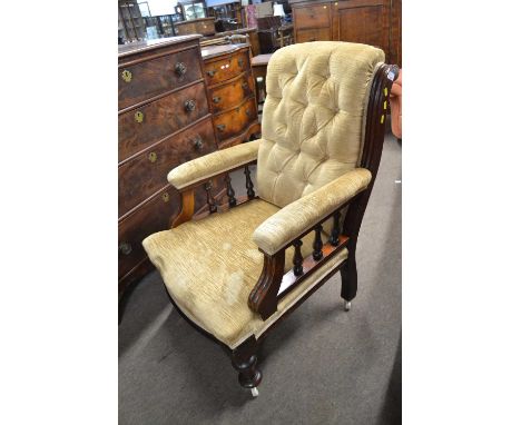 A late Victorian button upholstered armchair with turned legs and spindle decoration