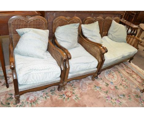 An early 20th Century hardwood framed bergere suite comprising a two seater sofa and two armchairs, largest piece 122cm wide