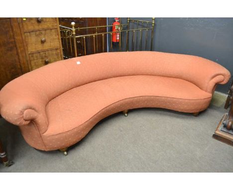 An unusual Victorian curved kidney shaped sofa raised on turned front legs with brass casters, 140cm wide