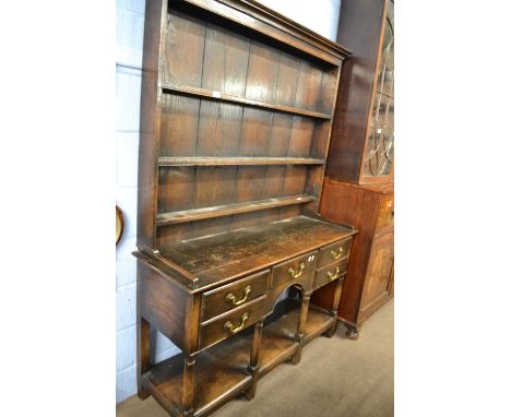 A small Georgian style oak dresser with three shelf back over a base with five drawers with swan neck handles, turned legs an