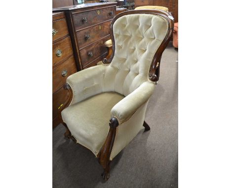 A Victorian walnut framed button back armchair upholstered in a mushroom coloured fabric raised on short cabriole legs