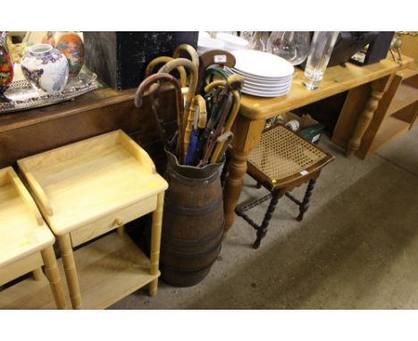 An oak and coopered stick stand with the contents of various walking sticks, a hockey stick and an ivory parasol