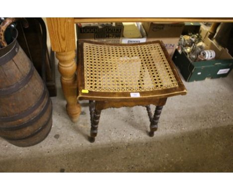 A cane seated stool raised on bobbin turned supports