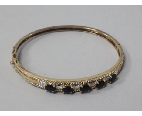A boxed 9ct gold, sapphire and diamond hinged bangle.