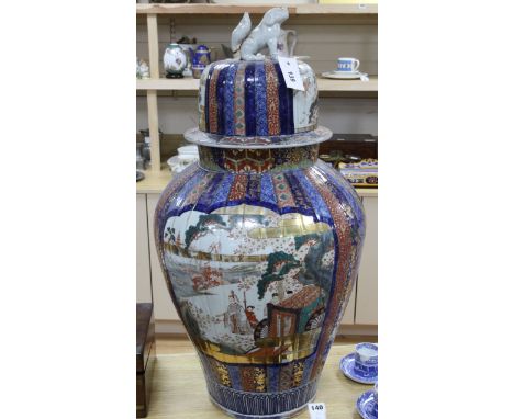 A large Japanese Imari fluted vase and cover, late 19th century, painted to each side with figures in a river landscape with 