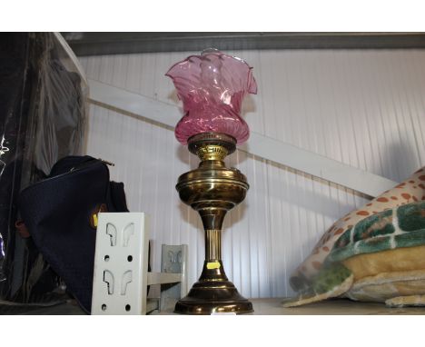 A brass Corinthian column oil lamp having cranberry glass shade