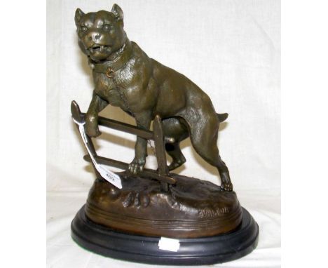 A reproduction bronze figure of a fierce dog up on a fence - stamped C Valton - 30cm high overall