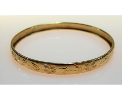 Yellow metal foliate engraved bangle, weight 6.4g approx.