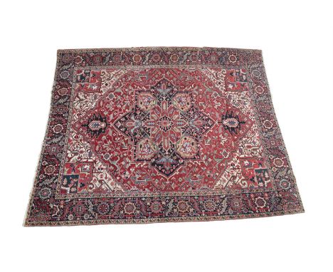 A PERSIAN STYLE RED GROUND WOOL RUG, emblazoned with a large foliate central medallion in navy and light blue tones, the enti