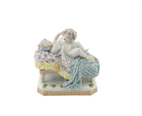 A 19TH CENTURY MEISSEN PORCELAIN GROUP OF DOG AND CHILD, the child lying on a raised bed with drapery playing with an inquisi