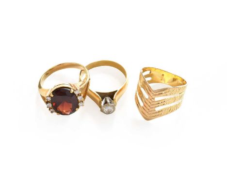A diamond solitaire ring, stamped '18CT', finger size N; a wishbone ring, stamped '750', finger size L1/2; and a garnet ring,