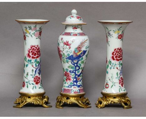 A garniture of three Chinese famille rose vases, Qianlong, painted with peonies and rocks, the central vase with a pair of ex