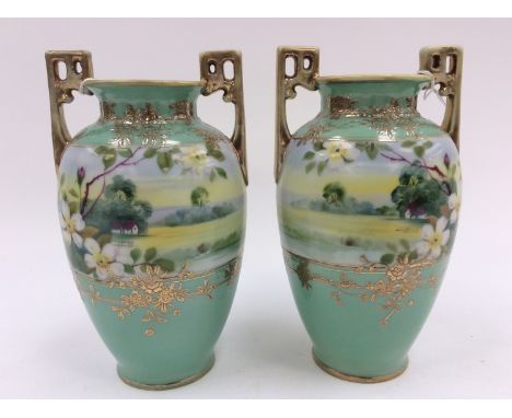 A pair of early 20th Century Noritake vases with twin handles, green ground, cottage scene and gilding detail 