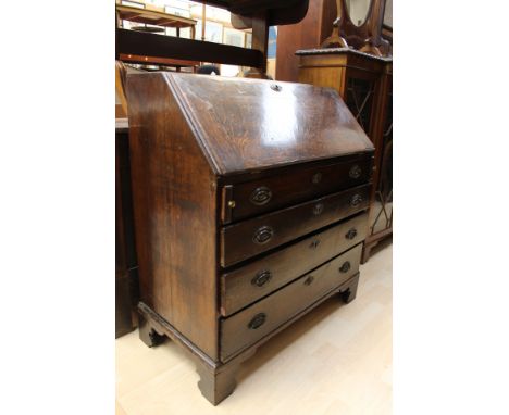 A George III oak bureau, the fall front enclosing a single door, the base with four graduated drawers, bracket feet