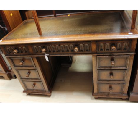 A 20th Century oak twin pedestal desk, with a leathered writing surface, the upper section with three drawers, the pedestals 