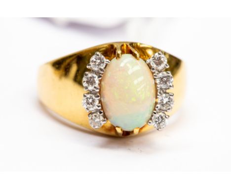 A yellow metal ring, illegible marks, probably 18ct gold, set with an oval opal with four claw set diamonds set either side, 