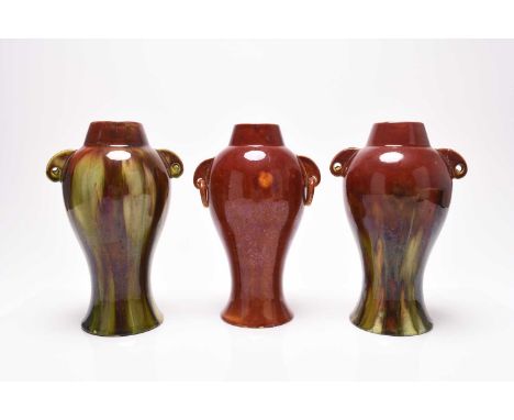 Three similar Burmantofts faience vases, late 19th century with red and steaked green glazes, with twin handles, one with rin