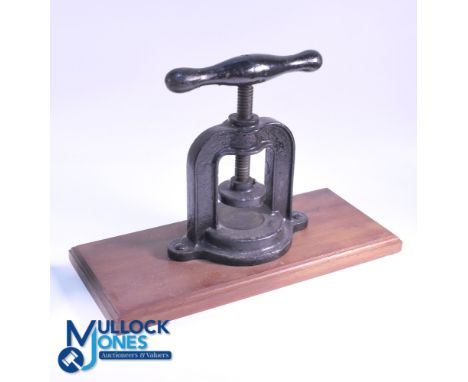 Cast-iron Golf Ball Press - horseshoe shaped mounted on a circular base, screwed to wooden base, retaining much of the origin