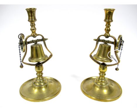 A Pair of XIX Century Brass Tavern Candlesticks, the columns with a swinging bell on a wheel bracket, raised on circular base