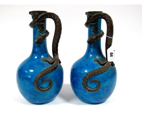 A Pair of Royal Worcester Aesthetic Movement Pottery Ewers, the turquoise scale grounds with applied brown and gilt lizard ha