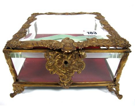An Art Nouveau Gilt Metal Trinket Box and Hinged Cover, of square footed form with bevelled glass panels, the mounts cast wit