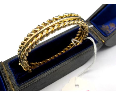 A Bangle, of twist design, hinged to snap clasp, stamped "15", in a J.W. Benson Ludgate Hill London Fitted Case. 