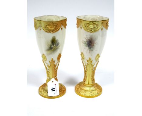 A Pair of Royal Worcester Porcelain Vases, of elongated lobed form raised on leaf moulded blush ivory and gilt stems and circ