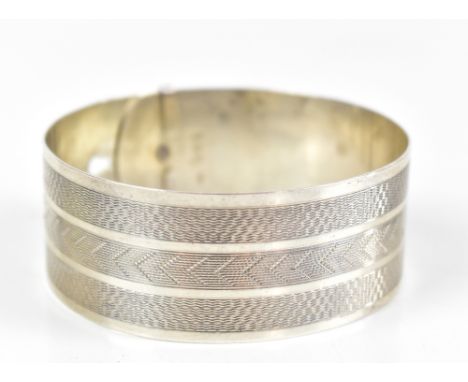 CHARLES HORNER; a George VI hallmarked silver bangle in the form of a belt, with engine turned detail, Chester 1944, approx 1