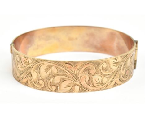 A 9ct yellow gold hinged bangle with chased detail to the front, internal diameter 5.7cm, approx 31.2g.Additional Information