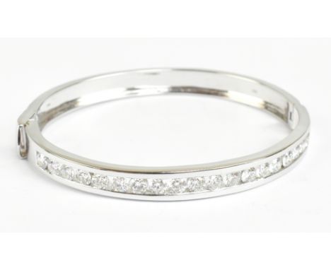 A good 18ct white gold and diamond hinged bangle, the nineteen round brilliant cut stones channel set to the upper portion of