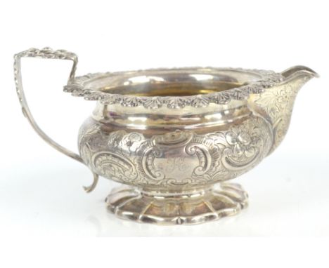 A George IV hallmarked silver cream jug of squat circular form with gilt washed interior, acanthus leaf scrolling handle and 
